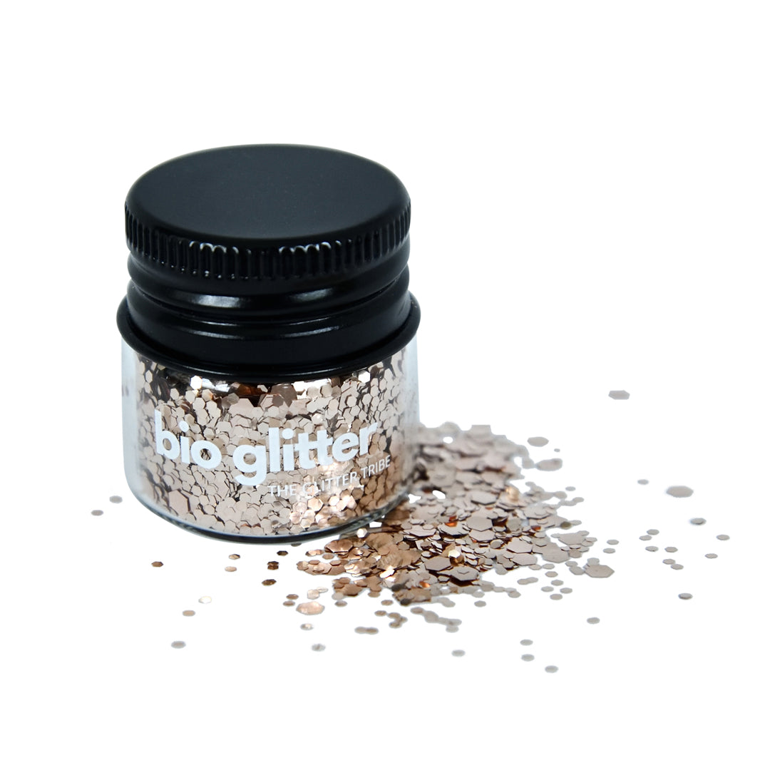 Rose gold bio glitter that is chunky and fine in a glass jar with a black lid.