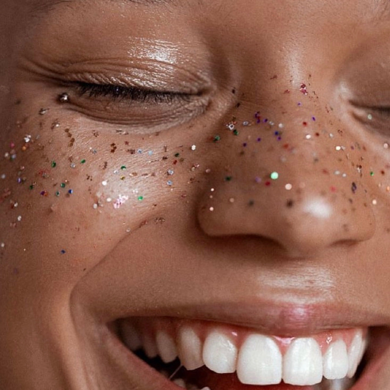 A smiling girl with white teeth wearing eco biodegradable glitter freckles from The Glitter Tribe 