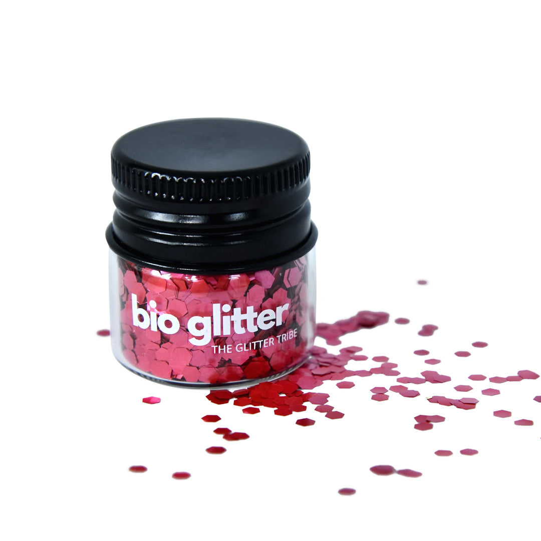 Red chunky  biodegradable glitter in a glass jar with a black lid with some red glitter at the side of jar.