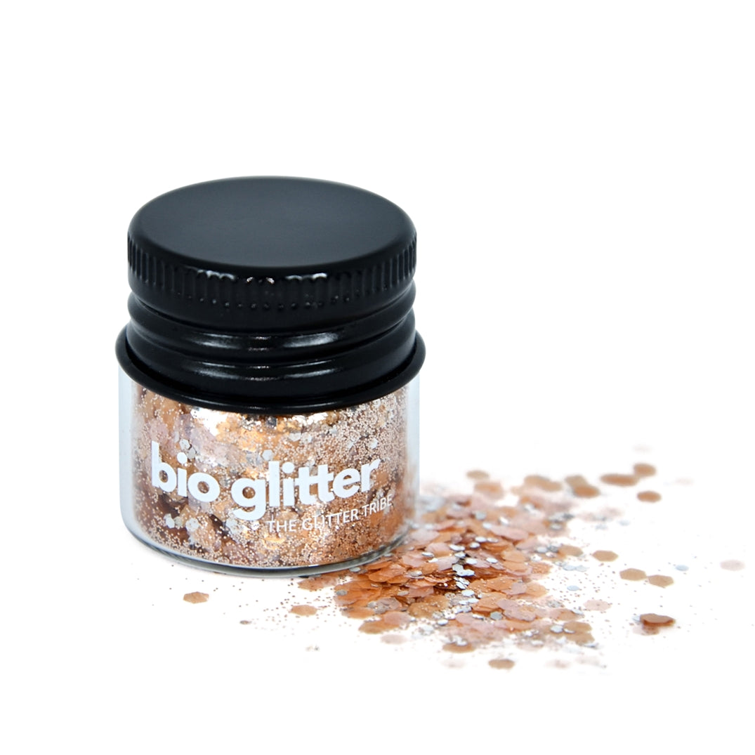 Gold and pink glitter in a glass jar with a black lid with glitter on the side of jar.