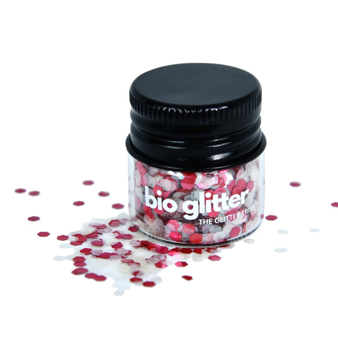 Red and white chunky bio glitter in a glass jar with a black lid. The glitter looks like a candy cane.