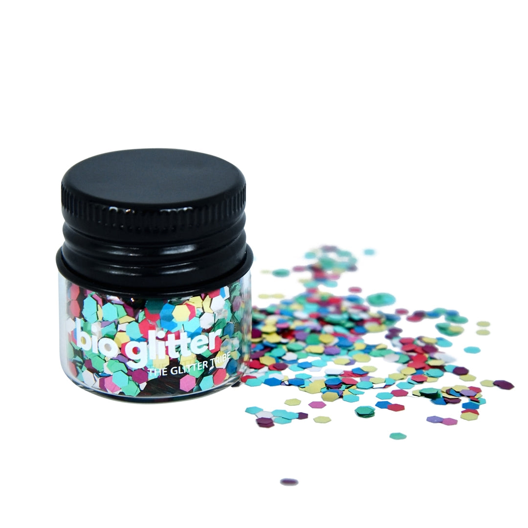 Rainbow bio glitter by The Glitter Tribe in a jar with a black lid on a white background with glitter spilling.