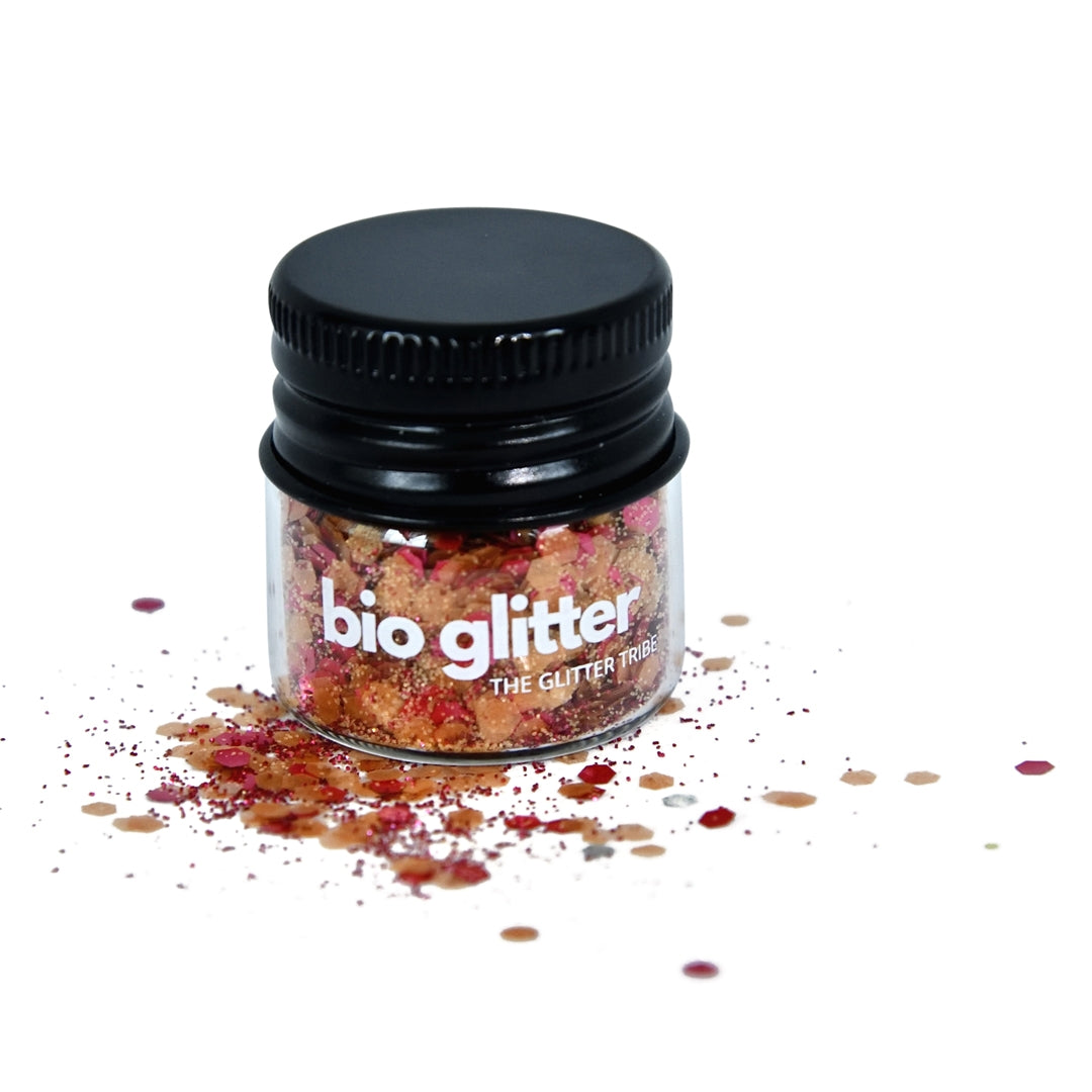 Red and orange bio glitter in a glass jar with a black lid on a white background.
