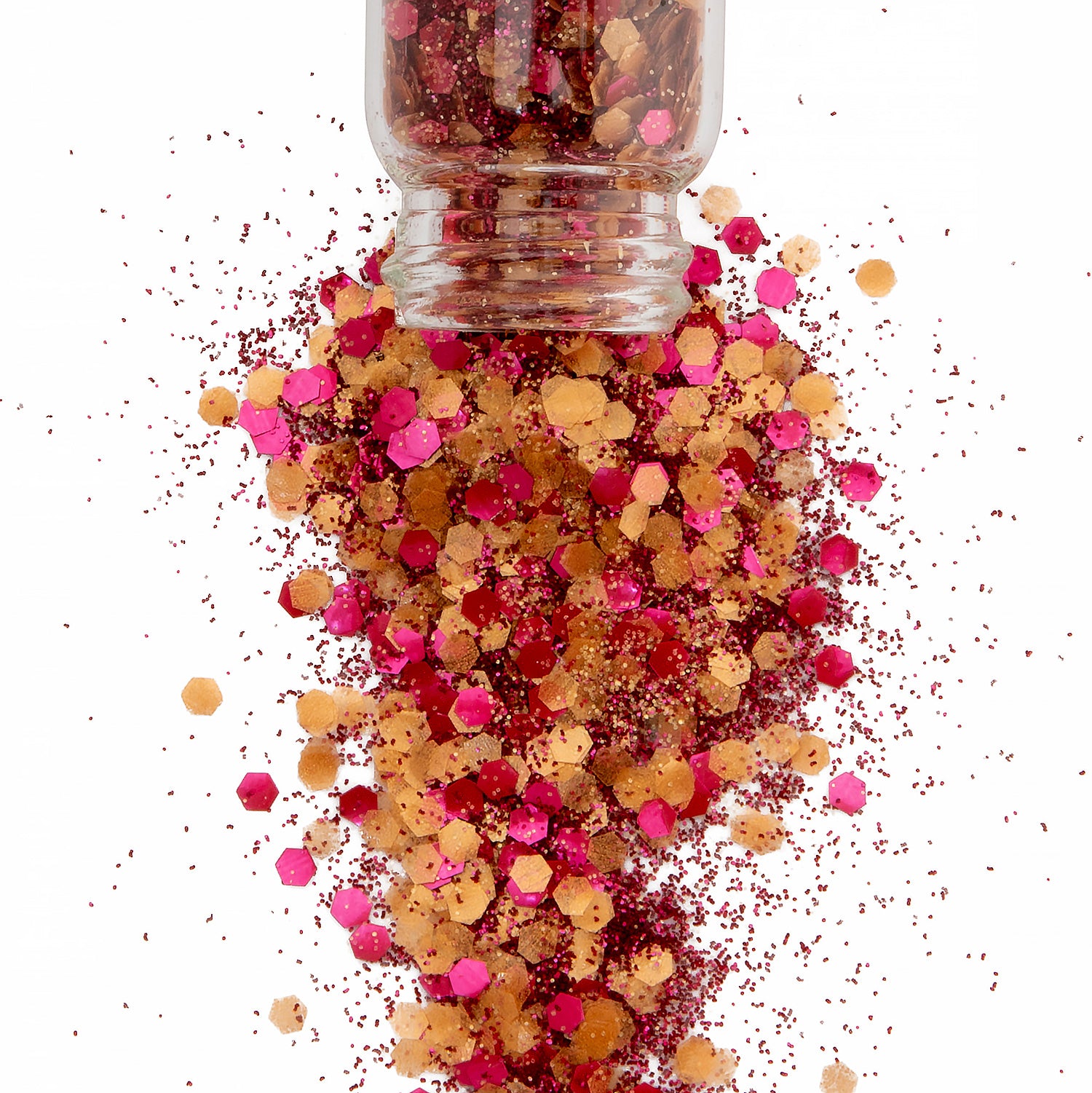 red and yellow chunky and fine bio glitter in a glass jar spilling onto a white background.
