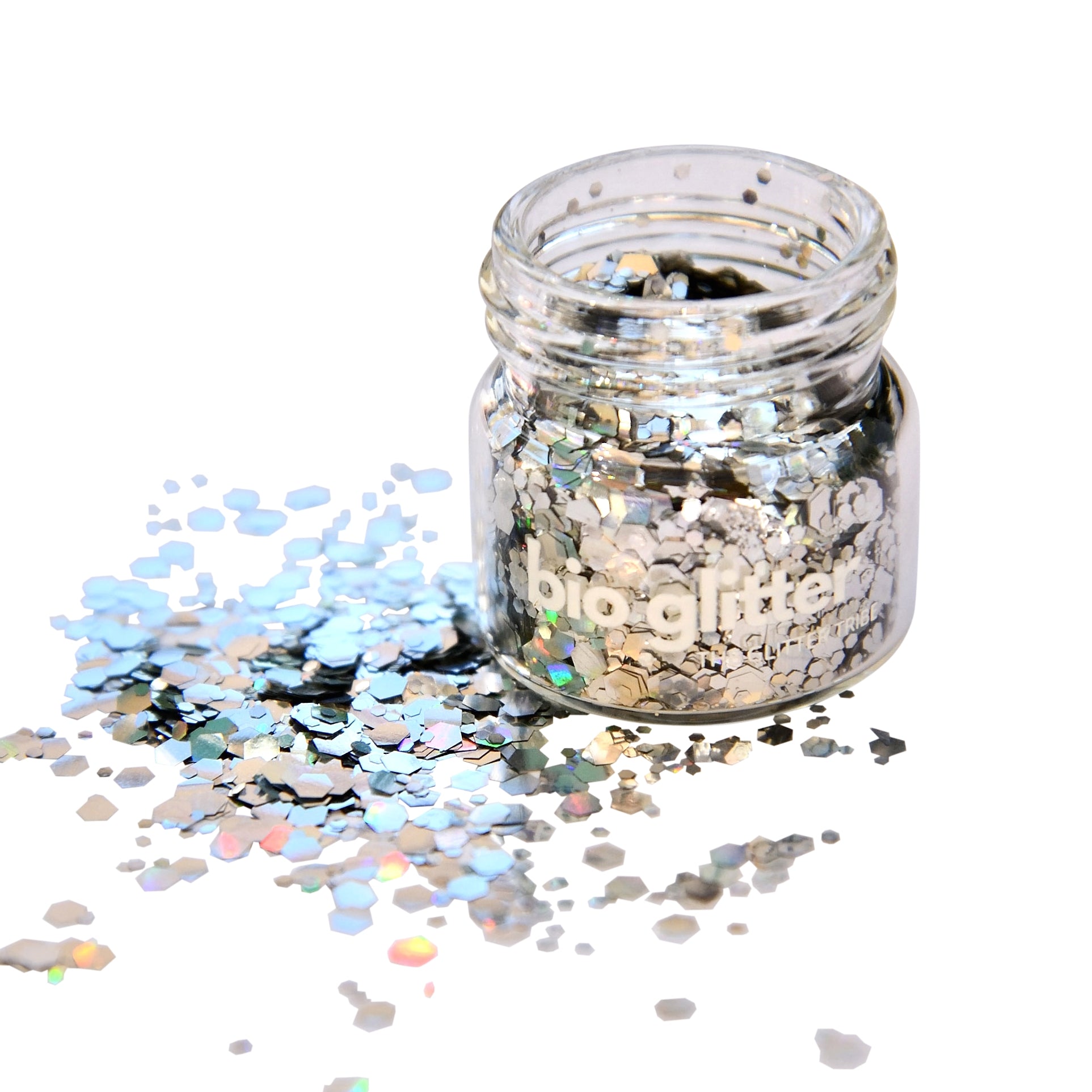 Holographic bioglitter in a glass jar with no lid reflecting light and colour onto a white serface.
