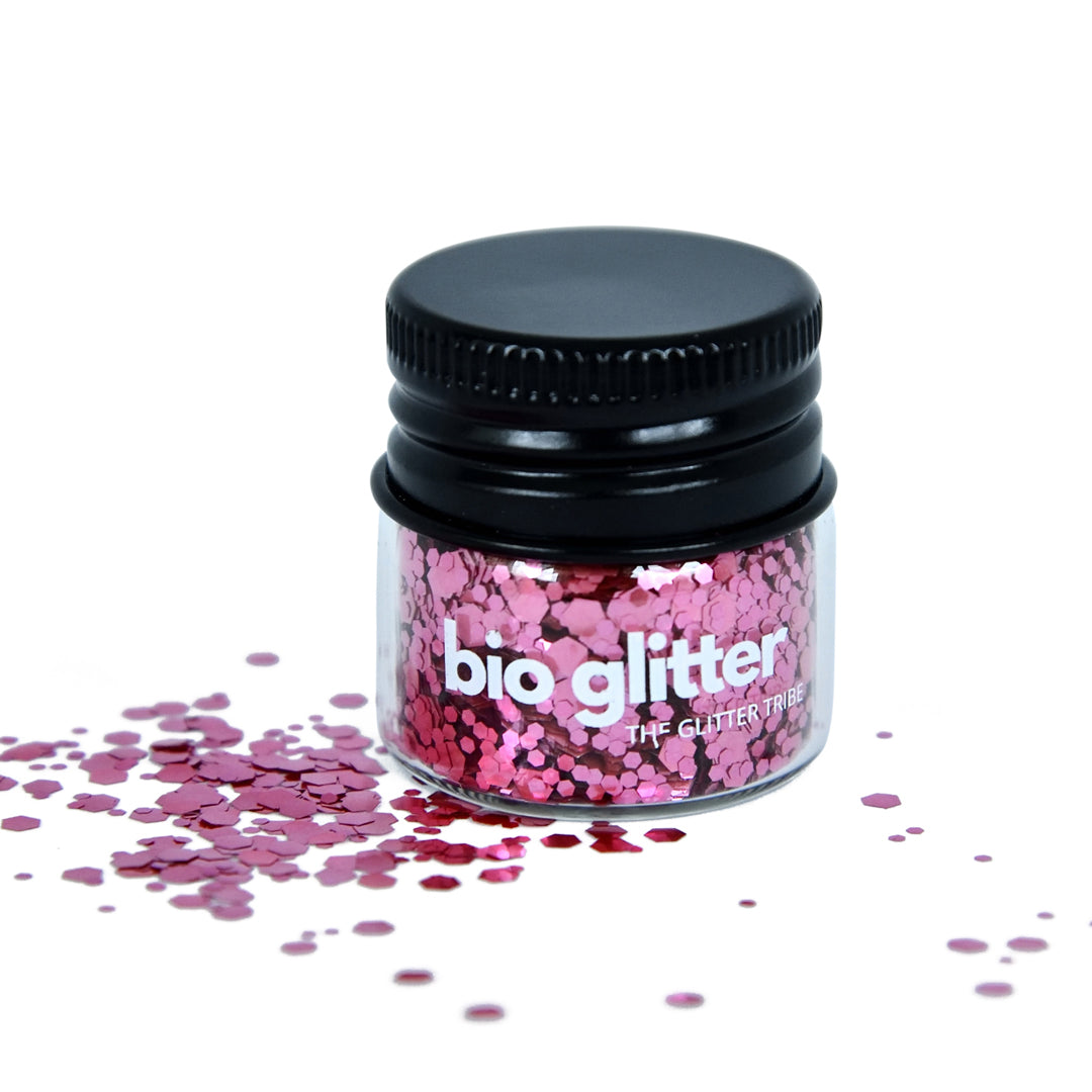 ROSE pink biodegradable glitter in a glass jar with a black lid on a white background.