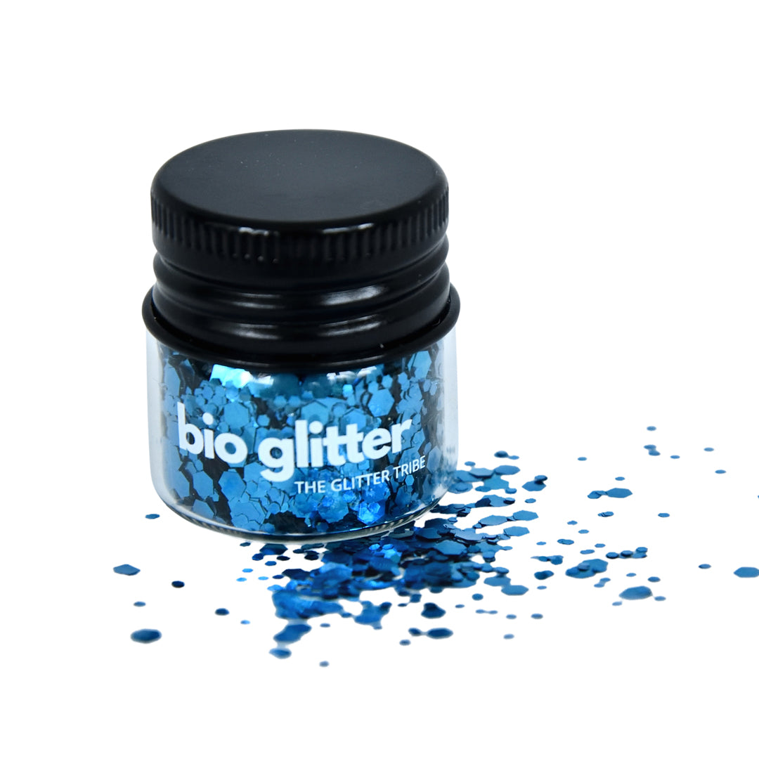 Bright blue bio glitter in a small glass jar with a black lid.
